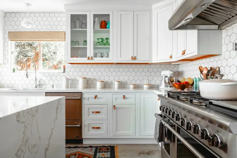 Bright kitchen with white cabinets, tiled walls, and a marble counter