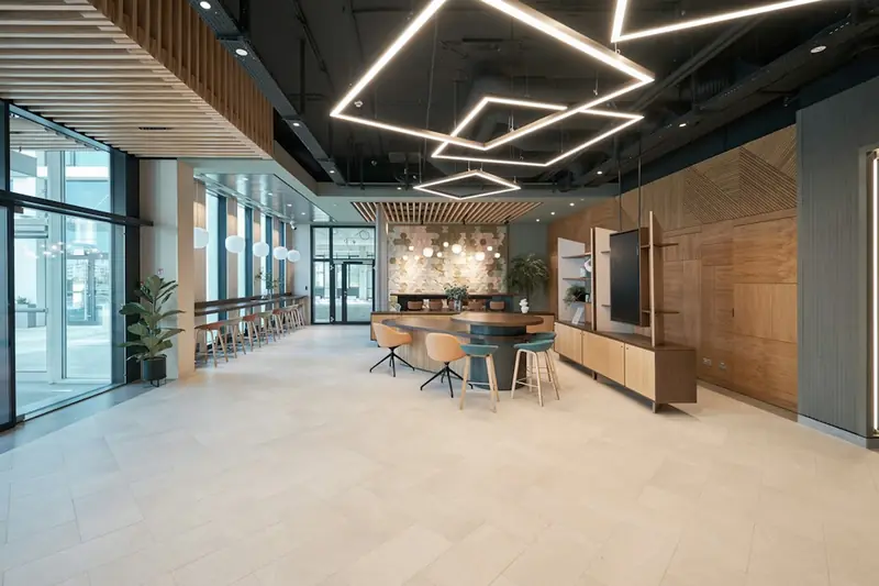 Open office lounge with tables, stools, and a light tiled floor