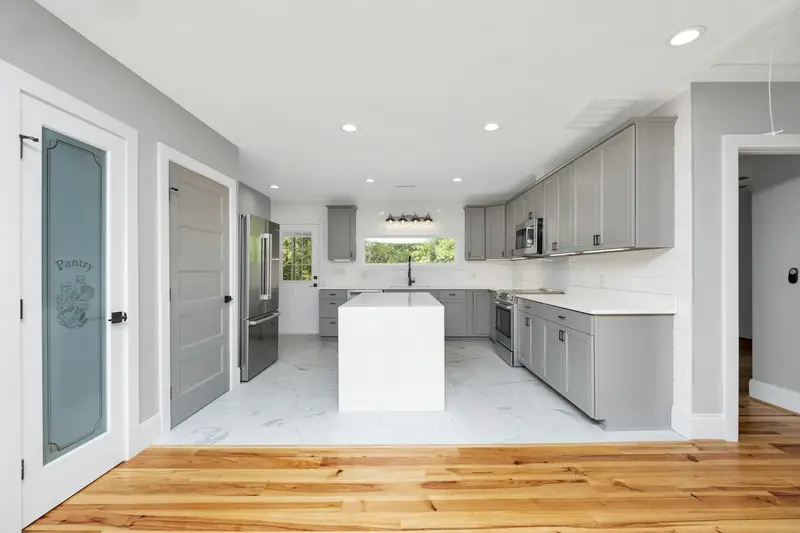 Bright new kitchen with white cabinets and wood floors in an empty home